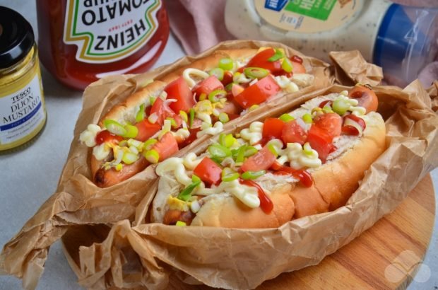 Domowy hot dog ze smażoną kiełbasą, pomidorami i zieloną cebulą